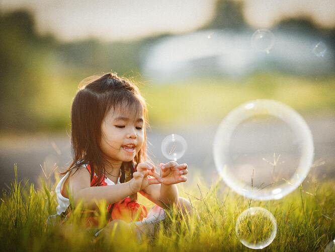 A girl blowing bubbles in a park