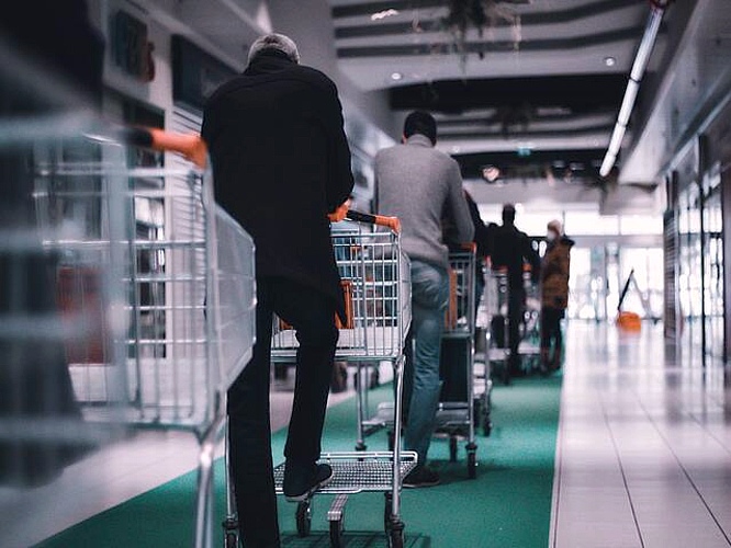 Men with shopping trolleys standing in queue