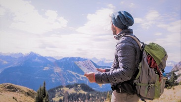 A man looking afar holding a map on a mountain