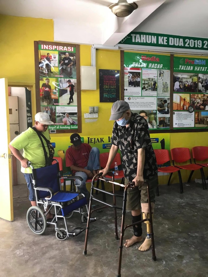Dua orang lelaki membantu seorang warga emas