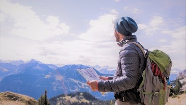 Seorang lelaki melihat jauh sedang memegang peta di atas gunung